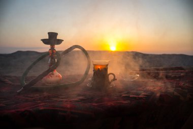 Nargile kömürü nargile kupa çöl de buhar bulutları açık yapma. Şark süsleme halı Doğu çay töreni üzerinde. Şık oryantal shisha günbatımı arka plan üzerinde. Seçici odak