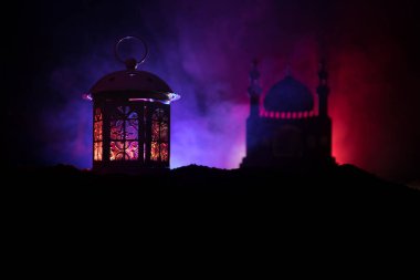Gece karanlık tonda sisli arka plan üzerinde parlayan mum yanan ile süs Arapça fener. Bayram tebrik kartı, Müslüman kutsal ay ramazan Kareem(Eid Holiday) koyu arka plan için davet.