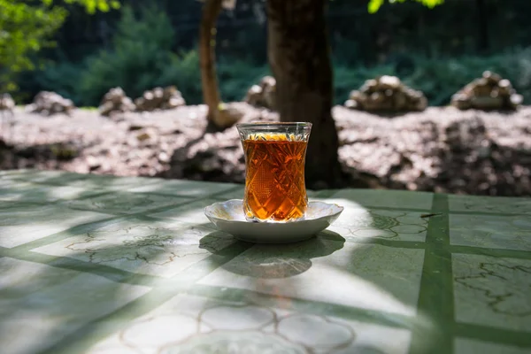 在森林里的桌子上玻璃上的东方红茶 东方茶的概念 Armudu 传统杯 绿色自然背景 选择性聚焦 — 图库照片
