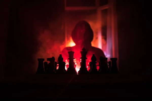 人在下棋 一个人在棋盘上的可怕模糊剪影与国际象棋数字 深色色调的雾背景 选择性对焦 恐怖概念 — 图库照片