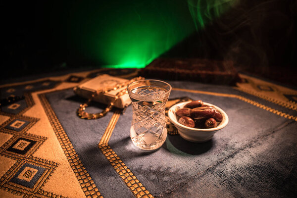 Water and dates. Iftar is the evening meal. View of decoration Ramadan Kareem holiday on carpet. Festive greeting card, invitation for Muslim holy month Ramadan Kareem. Selective focus
