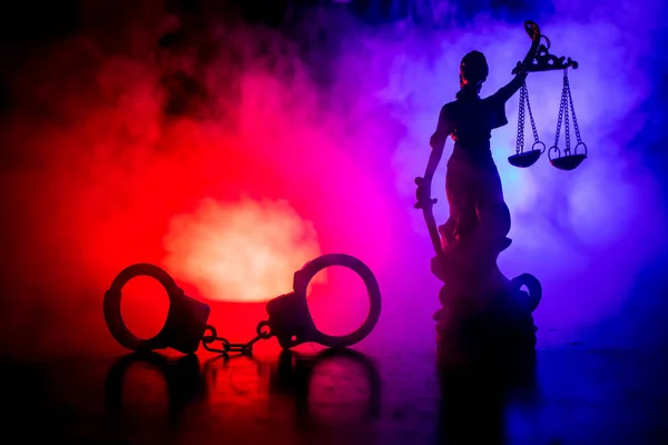 法的な法律概念 霧の背景に赤と青の警察ライトが点滅と裏側に正義の女神像と手錠のシルエット 選択と集中 — ストック写真