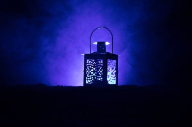 Gece karanlık tonda sisli arka plan üzerinde parlayan mum yanan ile süs Arapça fener. Bayram tebrik kartı, Müslüman kutsal ay ramazan Kareem(Eid Holiday) koyu arka plan için davet.