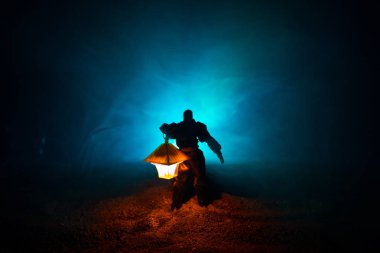 Yağmurluk ile onun el kavramı içinde parlayan fener karanlık ormanın gelen adam. Lamba korku katille silüeti. Dekorasyon