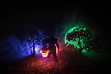 Yağmurluk ile onun el kavramı içinde parlayan fener karanlık ormanın gelen adam. Lamba korku katille silüeti. Dekorasyon