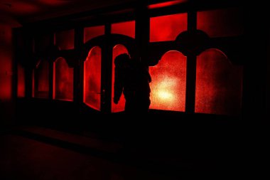 Kapalı cam bir kapıdan geçen, bilinmeyen bir gölge figürünün silueti. Geceleri pencerenin önündeki bir insanın silueti. Manyağın bulanık silueti korkunç cadılar bayramı konsepti.