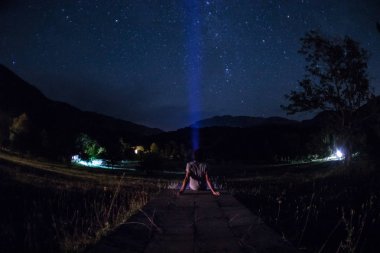 Adam gece ormanda silüeti. Işık ile karanlık ormanın içinde duran kişi silüeti. Karanlık gece ormanda. Gerçeküstü gece orman sahne. Korku Cadılar Bayramı kavramı.