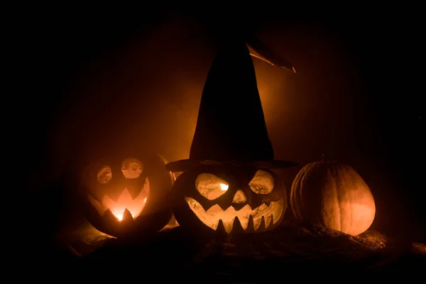 Group of Halloween Jack o Lanterns at night with a rustic dark foggy toned background. Selective focus