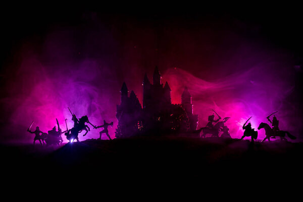 Средневековая боевая сцена с кавалерией и пехотой. Силуэты фигур как отдельные объекты, борьба между воинами на темном, тонированном туманном фоне со средневековым замком. Селективный фокус