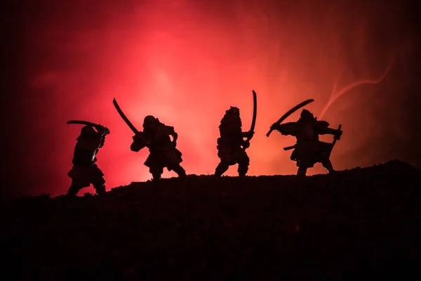 Silhouette of samurais with swords. Picture with four samurais and sunset sky. Selective focus