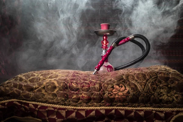 stock image Hookah hot coals on shisha bowl making clouds of steam at Arabian interior. Oriental ornament on the carpet. Stylish oriental shisha with backlight. For Shisha advertisement. Selective focus