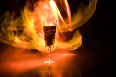 Şarap kadehi ateş kavram. Siyah arka plan üzerine yanan ateşi ile kırmızı şarap bir bardak. Seçici odak. Boş alan