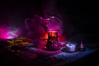 Nargile kömürü nargile kupa Arap iç de buhar bulutları yapma. Şark süsleme halı Doğu çay töreni üzerinde. Şık oryantal shisha içinde karanlık arka ışık ile. Seçici odak