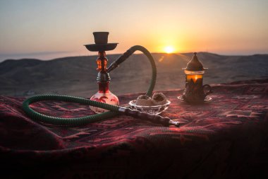 Nargile kömürü nargile kupa çöl de buhar bulutları açık yapma. Şark süsleme halı Doğu çay töreni üzerinde. Şık oryantal shisha günbatımı arka plan üzerinde. Seçici odak