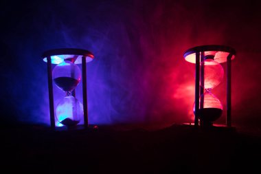 Zaman kavramı. Hourglasses siluetleri karanlık arka aydınlatma ile sisli arka plan tonda. Soyut gerçeküstü kavramı kopya alanı ile. Seçici odak