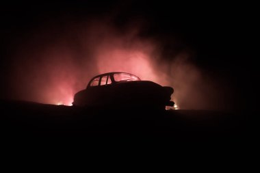 Eski eski model araba içinde karanlık sisli silüeti düşük ışıkta parlayan ışıklar ile arka plan tonda. Seçici odak