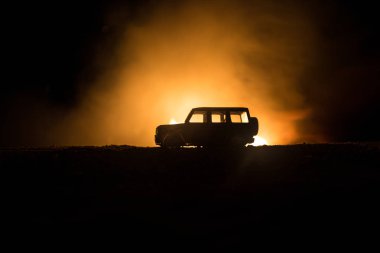 Koyu tonda sisli gökyüzü arka plan üzerinde roader jeep siluet. Araba ile gece ışık. Seçici odak