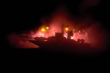 Deniz savaşı sahnesi. Karanlık sisli arka planda askeri savaş gemisinin silueti. Patlama ve yangın ile dramatik bir savaş sahnesi. Seçici odak