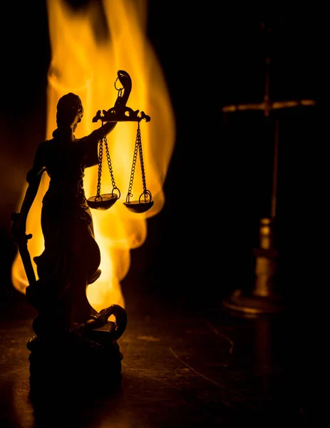 The Statue of Justice - lady justice or Iustitia / Justitia the Roman goddess of Justice on a dark fire background. Selective focus