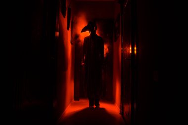 Ürpertici siluet koyu terk edilmiş binada. Korku Cadılar Bayramı kavramı. Karanlık koridor ortasında duran korku kişi silueti ile. Tonda ışık ve sis arka plan üzerinde.