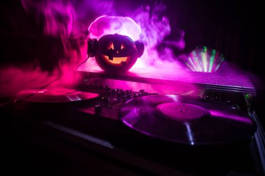 Cadılar Bayramı Balkabağı kopya alanı ile koyu arka plan üzerinde kulaklık ile bir dj tablo. Mutlu Cadılar Bayramı festival süsleri ve müzik konsepti. Boş alanı. Seçici odak