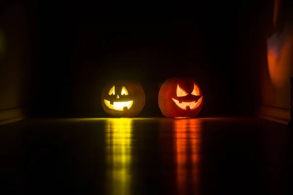 Halloween pumpkin head jack o lantern with glowing candles on background. Pumpkins on wooden floor. Selective focus