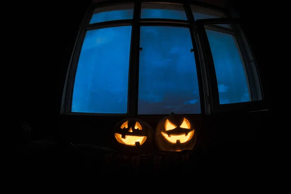 可怕的万圣节南瓜神秘房子窗口在晚上或万圣节南瓜在晚上在房间用蓝色的窗口中 万圣节的象征在窗口中 选择性的焦点 — 图库照片