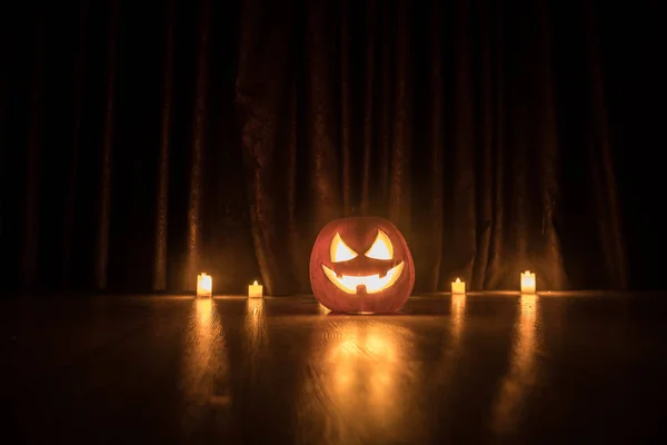 Halloween pumpkin head jack o lantern with glowing candles on background. Pumpkins on wooden floor. Selective focus