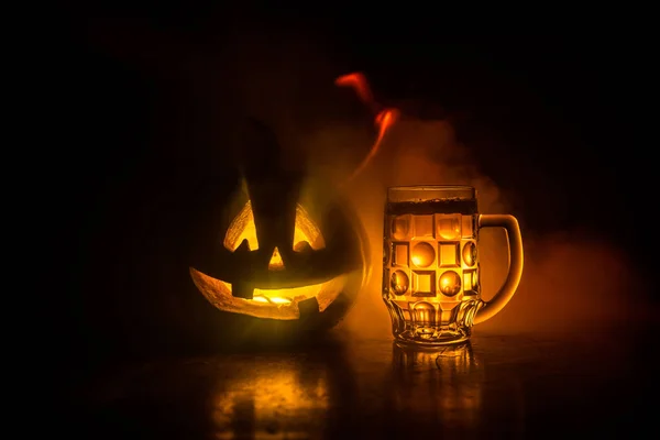 Glass of cold light beer with pumpkin on a wooden table for Halloween. Glass of fresh beer and pumpkin on a dark toned foggy background