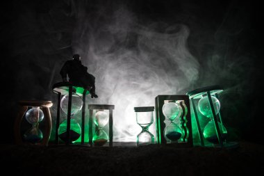 Zaman kavramı. Silhouette bir adam ve hourglasses duman ve ışıkları karanlık bir arka plan ile. Gerçeküstü bir şekilde dekore edilmiş fotoğraf.