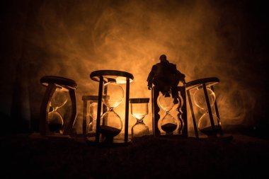 Zaman kavramı. Silhouette bir adam ve hourglasses duman ve ışıkları karanlık bir arka plan ile. Gerçeküstü bir şekilde dekore edilmiş fotoğraf.