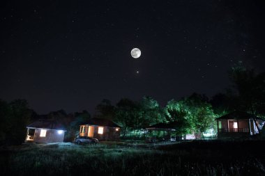 Binanın Orman geceleri ay veya vintage kır evi ile bulutlar ve yıldız ile gece dağ gece manzarası. Yaz gecesi. Uzun pozlama ile çekilen fotoğraf