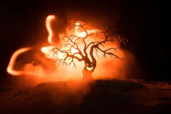 Silhouette of scary Halloween tree with horror face on dark foggy toned fire. Scary horror tree Halloween concept. Selective focus