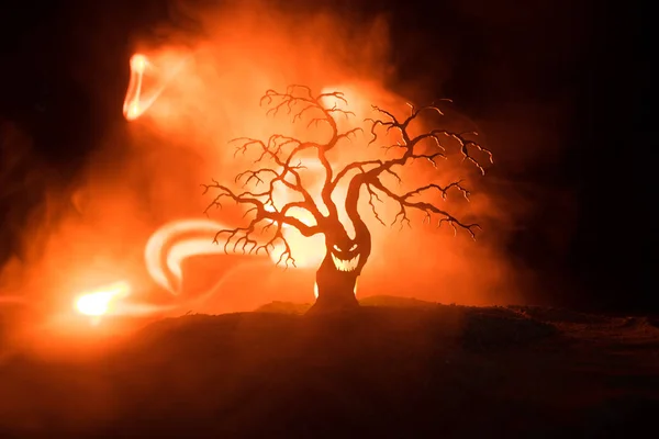 Silhouette of scary Halloween tree with horror face on dark foggy toned fire. Scary horror tree Halloween concept. Selective focus