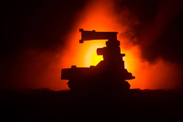 War Concept. Armored Tank Silhouette Below foggy fire sky at night. Attack scene. Toy decoration. Selective focus