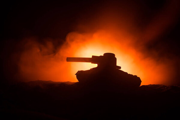 War Concept. Armored Tank Silhouette Below foggy fire sky at night. Attack scene. Toy decoration. Selective focus