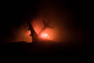 Uçak kazası. Düşen uçak yanıyor. Uçak yere çakıldı. Koyu renk arka planda oyuncaklarla süslenmiş. Uçak kazası konsepti. Seçici odak