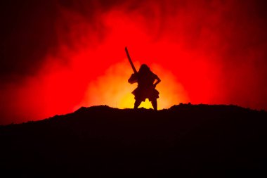 Savaşçı bir kılıç siluet bir gökyüzü ninja ile. Samuray koyu tonda sisli arka plan ile dağın zirvesinde. Seçici odak