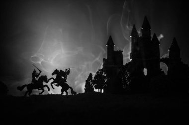 Süvari ve piyade ile ortaçağ savaş sahnesi. Siluetleri şekiller ayrı nesneler olarak mücadele eski Gotik kale ile koyu tonda sisli arka plan savaşçılar arasında