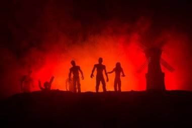 Aç zombiler ve karanlık sisli tonda gökyüzü karşı tepede eski fırıldak siluetleri kalabalık. Siluetleri korkunç zombi gece yürüyüş. Korku kavramı