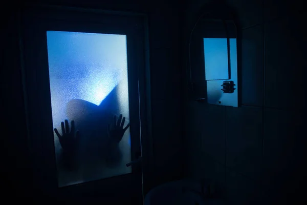 Horror silhouette of woman in window. Scary halloween concept Blurred silhouette of witch in bathroom