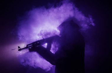 Saldırı tüfeği koyu tonda sisli arka plan veya tehlikeli bir haydut silah elinde tutan saldırmaya hazır olan adam silüeti. Terörist silah Tema dekor ile çekim