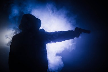 Tabanca dark saldırı için hazır olan adam silüeti sisli arka plan veya tehlikeli bir haydut holding silahı elinde tonda. Terörist silah Tema dekor ile çekim