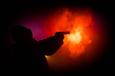 Tabanca dark saldırı için hazır olan adam silüeti sisli arka plan veya tehlikeli bir haydut holding silahı elinde tonda. Terörist silah Tema dekor ile çekim