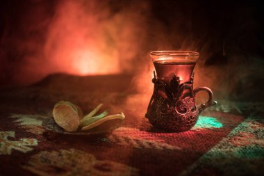 Cam bir halı ile ışık ve duman koyu arka plan üzerinde Doğu snacks ile Arap tea. Doğu çay kavramı. Boş alanı. Seçici odak.