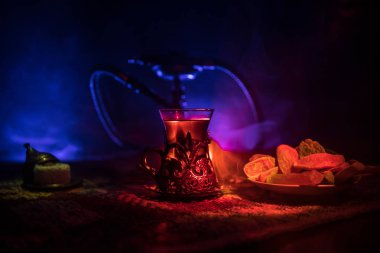 Nargile kömürü nargile kupa Arap iç de buhar bulutları yapma. Şark süsleme halı Doğu çay töreni üzerinde. Şık oryantal shisha içinde karanlık arka ışık ile. Seçici odak