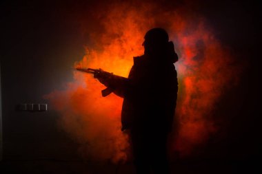Saldırı tüfeği koyu tonda sisli arka plan veya tehlikeli bir haydut silah elinde tutan saldırmaya hazır olan adam silüeti. Terörist silah Tema dekor ile çekim