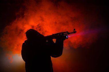 Saldırı tüfeği koyu tonda sisli arka plan veya tehlikeli bir haydut silah elinde tutan saldırmaya hazır olan adam silüeti. Terörist silah Tema dekor ile çekim
