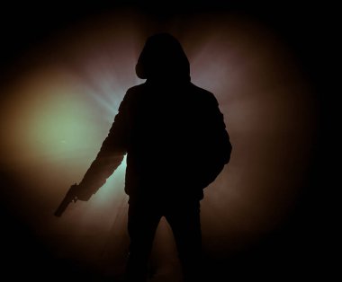 Tabanca dark saldırı için hazır olan adam silüeti sisli arka plan veya tehlikeli bir haydut holding silahı elinde tonda. Terörist silah Tema dekor ile çekim
