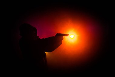 Tabanca dark saldırı için hazır olan adam silüeti sisli arka plan veya tehlikeli bir haydut holding silahı elinde tonda. Terörist silah Tema dekor ile çekim